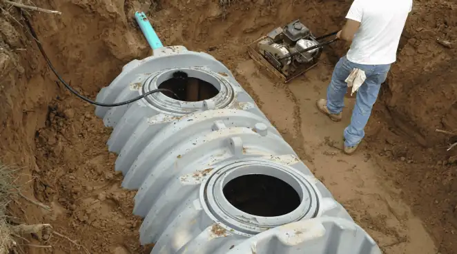 Septic tank installation showing a technician compacting soil around a new poly septic tank in an excavation pit in ,